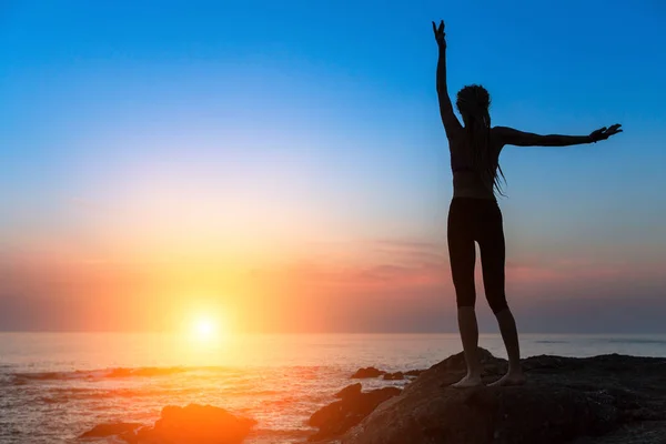 Joogaa auringonlaskun aikaan harjoittava nainen. tekijänoikeusvapaita kuvapankkikuvia