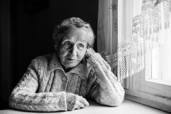 Ηλικιωμένη γυναίκα που κάθεται στο τραπέζι — Φωτογραφία Αρχείου