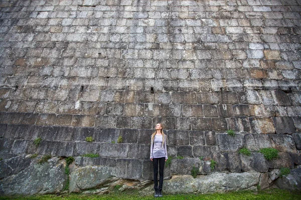 Mujer de pie cerca de pared de piedra . —  Fotos de Stock