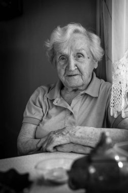 Yaşlı kadın masada oturuyor..