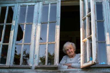 yaşlı kadın penceresinden görünüyor