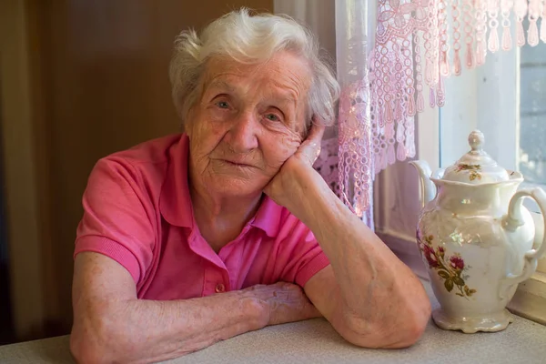Пожилая женщина сидит за столом — стоковое фото