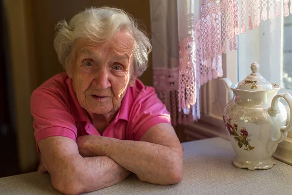 Oudere vrouw aan de keukentafel. — Stockfoto