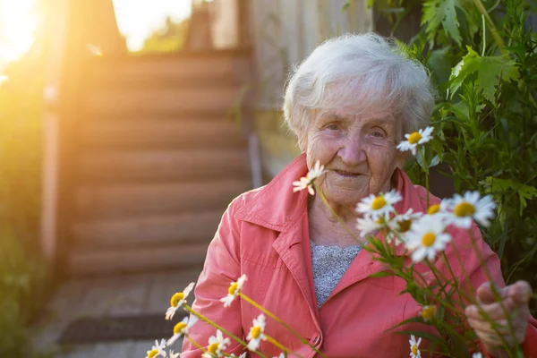 Bejaarde vrouw in de buurt van dorpshuis — Stockfoto