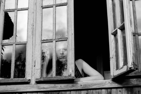 Mujer joven mirando por la ventana — Foto de Stock