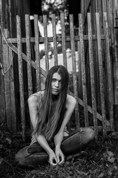 Vrouw zitten in de buurt van het houten hek — Stockfoto