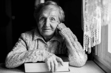 Bir kitapla oturan yaşlı kadın.