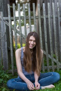 Genç bir kadın çimenlerde oturuyor.