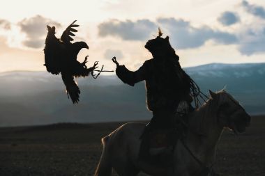 Siluet ise bir altın kartal içinde çöl Dağ Batı Moğolistan ile avcılık kartal avcı geleneksel giyim.