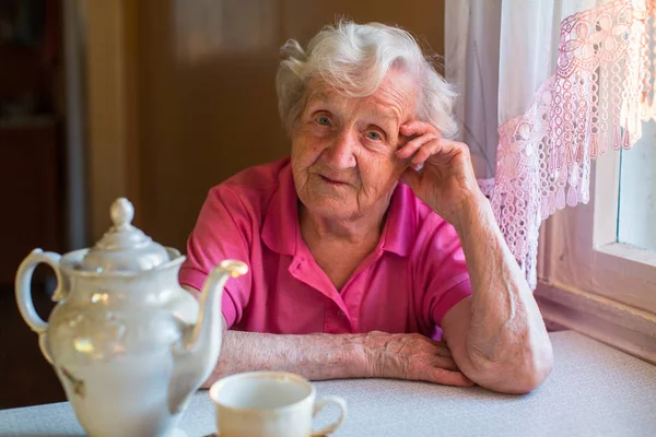 Femme âgée assise à la table — Photo