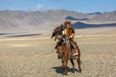 Bayan Ulgiy, Moğolistan-27 Eylül, 2017: Kazak kartal avcı ise içinde çöl Dağ Batı Moğolistan kolunda altın kartal tutan tavşan için avcılık sırtında geleneksel kıyafetleri.