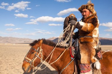 Bayan Ulgiy, Moğolistan-27 Eylül, 2017: Kazak kartal avcı geleneksel kıyafetleri, ise içinde çöl Dağ Batı Moğolistan kolunda altın kartal tutan tavşan için avcılık.