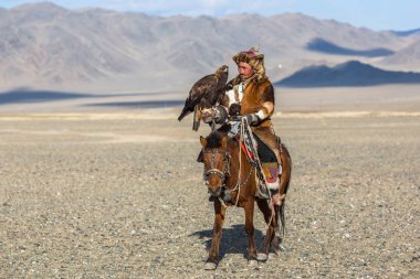Bayan Ulgiy, Moğolistan-27 Eylül, 2017: Kazak kartal avcı ise içinde çöl Dağ Batı Moğolistan kolunda altın kartal tutan tavşan için avcılık sırtında geleneksel kıyafetleri.