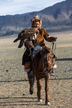 Bayan Ulgiy, Moğolistan-27 Eylül, 2017: Kazak kartal avcı ise içinde çöl Dağ Batı Moğolistan kolunda altın kartal tutan tavşan için avcılık sırtında geleneksel kıyafetleri.
