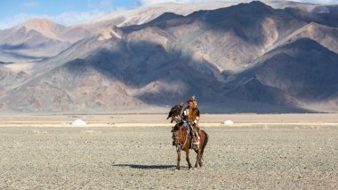 Bayan Ulgiy, Moğolistan-27 Eylül, 2017: Kazak kartal avcı ise içinde çöl Dağ Batı Moğolistan kolunda altın kartal tutan tavşan için avcılık sırtında geleneksel kıyafetleri.