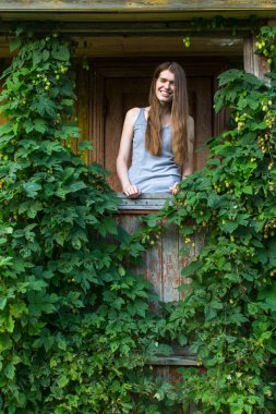 Yaz terasında uzun saçlı genç kadın ile yeşilliklerle kaplı.