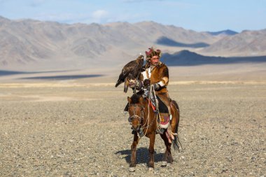 Bayan Ulgiy, Moğolistan-27 Eylül, 2017: Kazak kartal avcı ise içinde çöl Dağ Batı Moğolistan kolunda altın kartal tutan tavşan için avcılık sırtında geleneksel kıyafetleri.