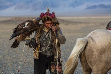 Sagsay, Moğolistan - 28 Eylül 2017: Altın Kartal avcı geleneksel kıyafetleri, ise bir Altın Kartallar kollarını içinde çöl Dağ Batı Moğolistan üzerinde tutarak tavşan için avcılık.
