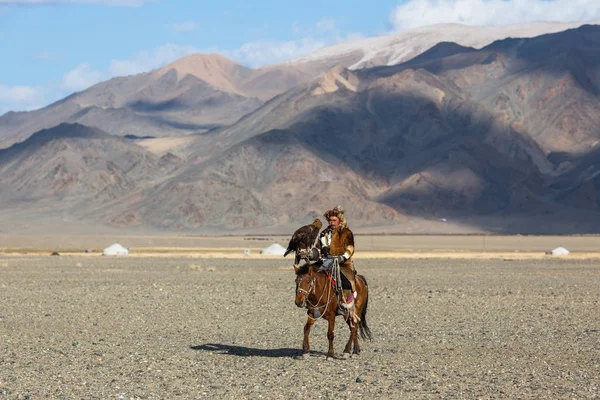 Bayan Ulgiy, Moğolistan-27 Eylül, 2017: Kazak kartal avcı ise içinde çöl Dağ Batı Moğolistan kolunda altın kartal tutan tavşan için avcılık sırtında geleneksel kıyafetleri.