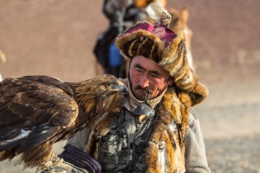 Sagsay, Moğolistan - 28 Eylül 2017: Altın Kartal avcı ise bir Altın Kartallar kollarını içinde çöl Dağ Batı Moğolistan üzerinde tutarak tavşan için avcılık.