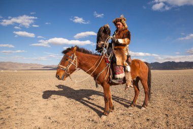 Bayan Ulgiy, Moğolistan-27 Eylül, 2017: Kazak kartal avcı ise içinde çöl Dağ Batı Moğolistan kolunda altın kartal tutan tavşan için avcılık sırtında geleneksel kıyafetleri.