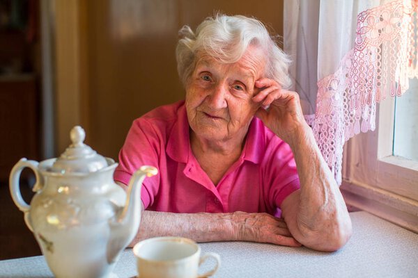 Portrait of an elderly woman behind a dining table.