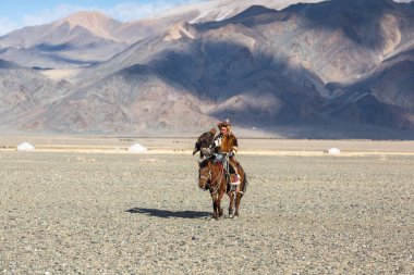 Bayan Ulgiy, Moğolistan-27 Eylül, 2017: Kazak kartal avcı ise içinde çöl Dağ Batı Moğolistan kolunda altın kartal tutan tavşan için avcılık sırtında geleneksel kıyafetleri.