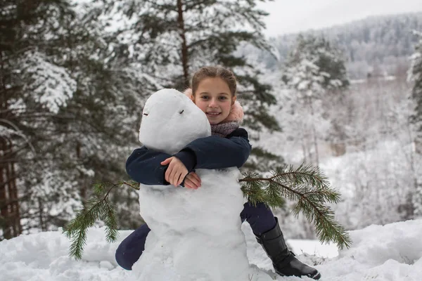 かわいい女の子は 雪に覆われた冬の公園で雪だるまを Sculpts します — ストック写真