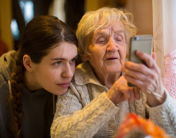 Oudere Vrouw Met Volwassen Kleindochter Kijkt Naar Een Smartphone — Stockfoto