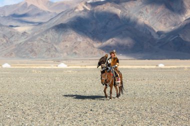 Bayan Ulgiy, Moğolistan-27 Eylül, 2017: Kazak kartal avcı ise içinde çöl Dağ Batı Moğolistan kolunda altın kartal tutan tavşan için avcılık sırtında geleneksel kıyafetleri.