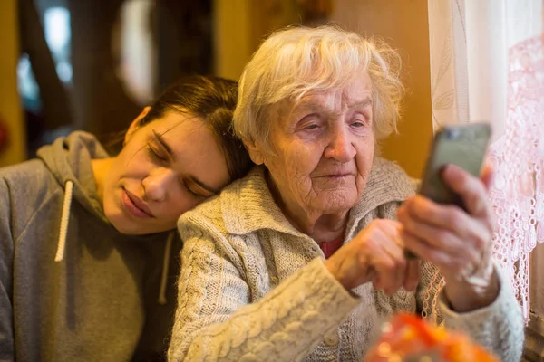 Ältere Frau Blickt Mit Erwachsener Enkelin Auf Smartphone — Stockfoto