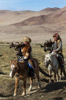 Sagsay, Moğolistan - 28 Eylül 2017: Kartal avcılar geleneksel kıyafetleri, ise bir Altın Kartallar kollarını içinde çöl Dağ Batı Moğolistan üzerinde tutarak tavşan için avcılık.
