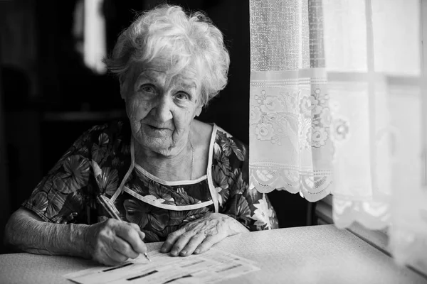 yaşlı kadın faturalar ödenmesi için fatura doldurur.