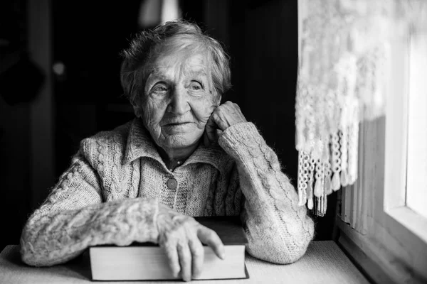 Femme Âgée Avec Livre Main Assis Une Table Près Fenêtre — Photo