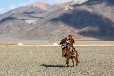 Bayan Ulgiy, Moğolistan-27 Eylül, 2017: Kazak kartal avcı ise içinde çöl Dağ Batı Moğolistan kolunda altın kartal tutan tavşan için avcılık sırtında geleneksel kıyafetleri.
