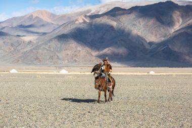 Bayan Ulgiy, Moğolistan-27 Eylül, 2017: Kazak kartal avcı ise içinde çöl Dağ Batı Moğolistan kolunda altın kartal tutan tavşan için avcılık sırtında geleneksel kıyafetleri.