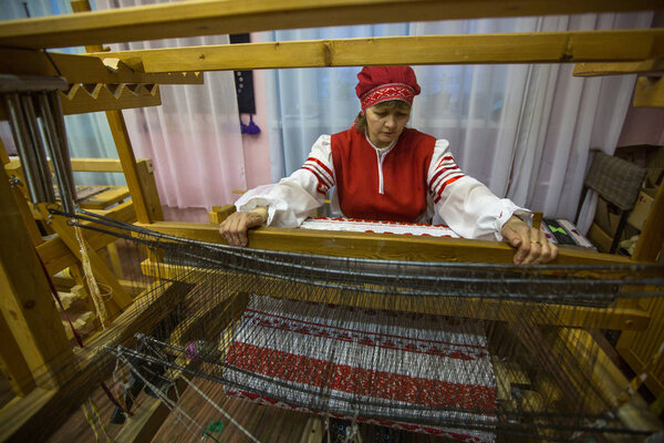 VAZHINY, LENINGRAD REGION, RUSSIA - DEC 21, 2017: Weaver while working in the Textile Studio of decorative art "Tekstilnaya Plastika", at municipal budgetary institution of culture.