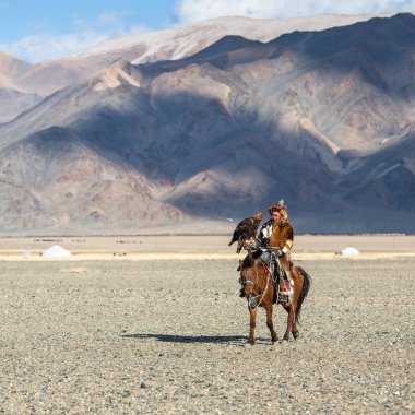 Bayan Ulgiy, Moğolistan-27 Eylül, 2017: Kazak kartal avcı ise içinde çöl Dağ Batı Moğolistan kolunda altın kartal tutan tavşan için avcılık sırtında geleneksel kıyafetleri.