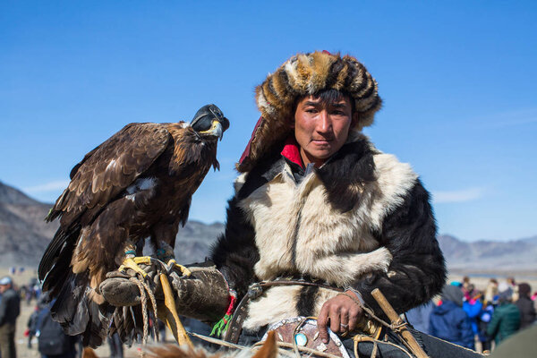 ОЛГИЙ, МОНГОЛИЯ - 30 сентября 2017 года: традиционная одежда Казахского охотника на орлов, с золотым орлом во время ежегодных национальных соревнований с хищными птицами "Беркутчи" Западной Монголии
.
