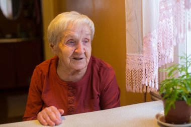 Yaşlı kadın masada oturuyor..