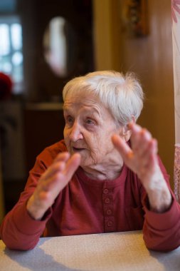 duygusal olarak masada oturan yaşlı bir kadın.