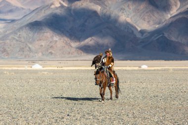 Bayan Ulgiy, Moğolistan-27 Eylül, 2017: Kazak kartal avcı ise içinde çöl Dağ Batı Moğolistan kolunda altın kartal tutan tavşan için avcılık sırtında geleneksel kıyafetleri.