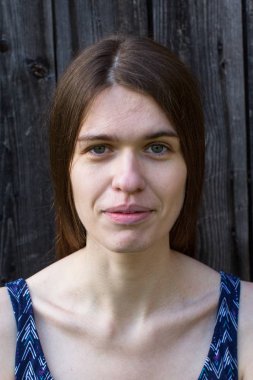 Uzun saçlı tatlı genç bir kadınla ön portresi. Ahşap duvar arka plan üzerinde.