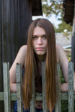 Ahşap çit köyü yakınlarında uzun kahverengi saçlı genç kadın portre.