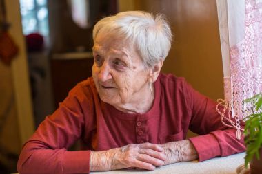 Yaşlı kadın masada oturuyor..