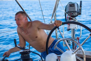 Genç adam bir yelkenli tekne dümen tekne.