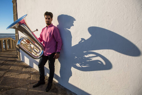 Musician with Tuba near the white wall the shadow of the tool.