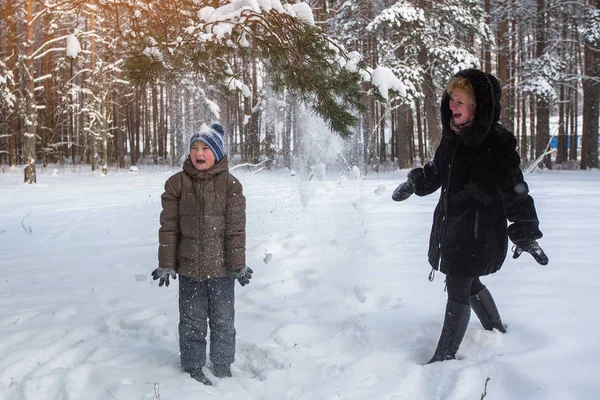 雪に覆われた冬の公園で男の子と遊ぶ若い女性 — ストック写真