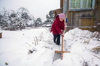 Yaşlı kadın kar kırsal house yakınındaki temizler.