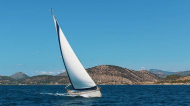 Yacht boat with white sails in the Sea near the coasts of the Islands.